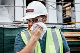 construction worker on a job site wiping face with cleaning wipes